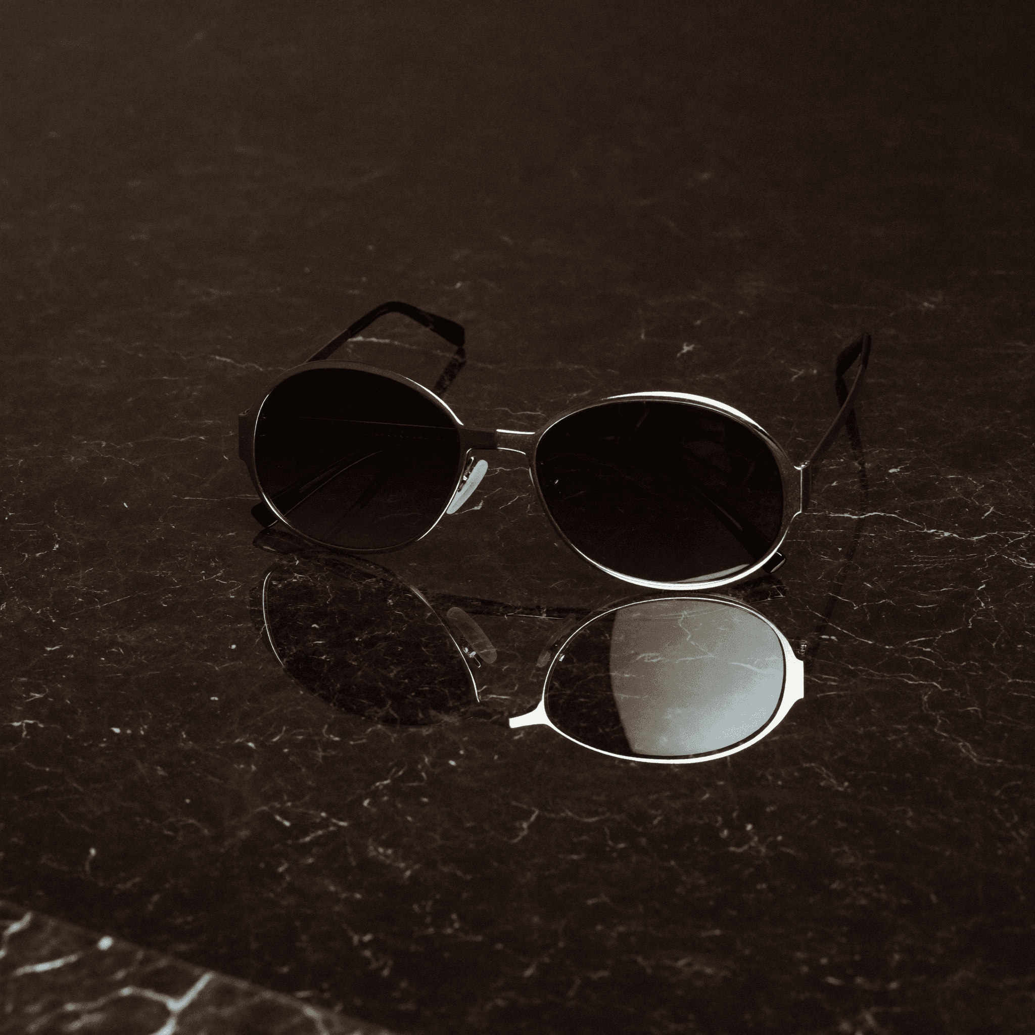 Luxury sunglasses on reflective marble surface